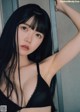 A woman with long black hair wearing a black bra.
