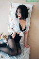 A woman sitting on top of a bed wearing black stockings.