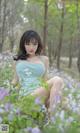 A woman in a blue dress sitting in a field of flowers.