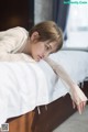 A woman laying on top of a bed next to a window.