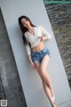 A woman in a white top and denim shorts posing for a picture.