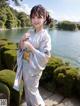 A woman in a blue kimono standing by a body of water.