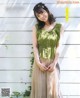 A woman in a green top and pleated skirt posing for a magazine.