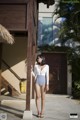 A woman in a white bodysuit standing in front of a building.